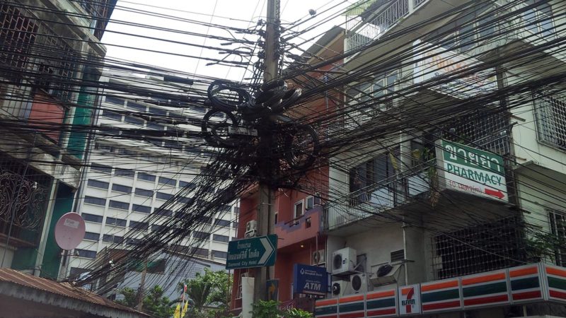 A tangle of many wires hanging on a pole in Bangkok